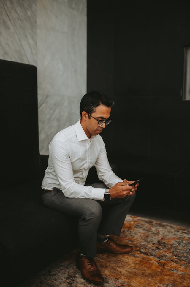 Professional sitting and casually checking his phone before a meeting