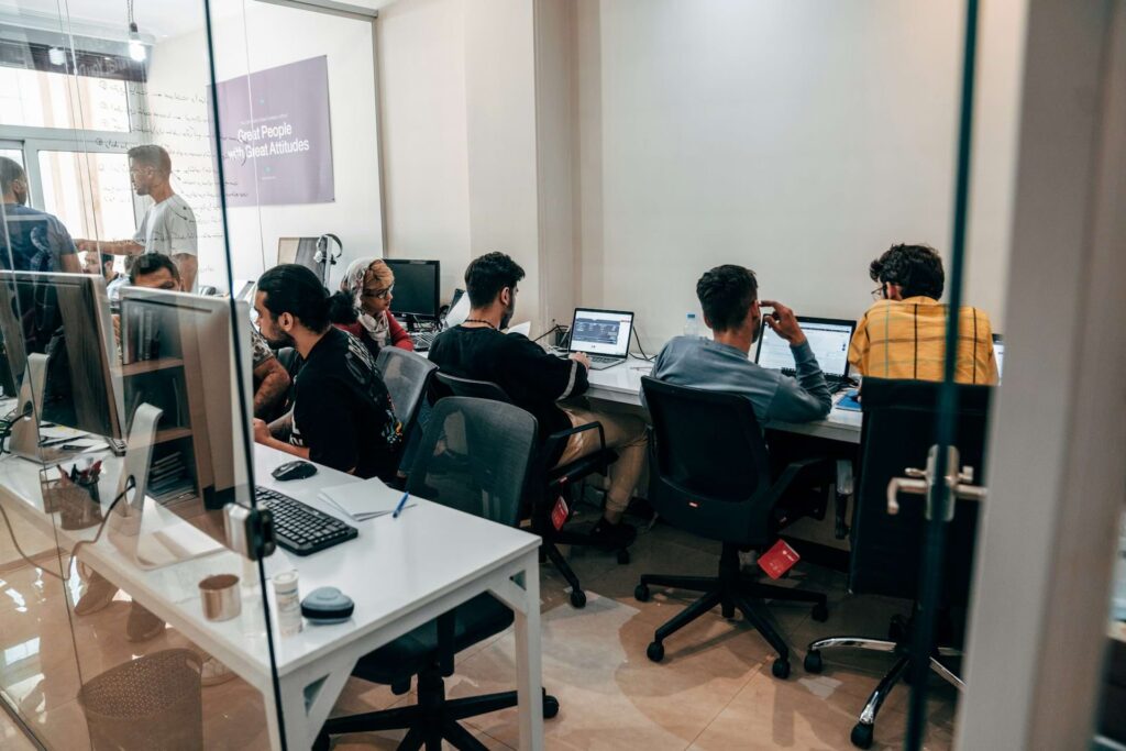 Team of professionals working in a similar office setup with identical desks and laptops