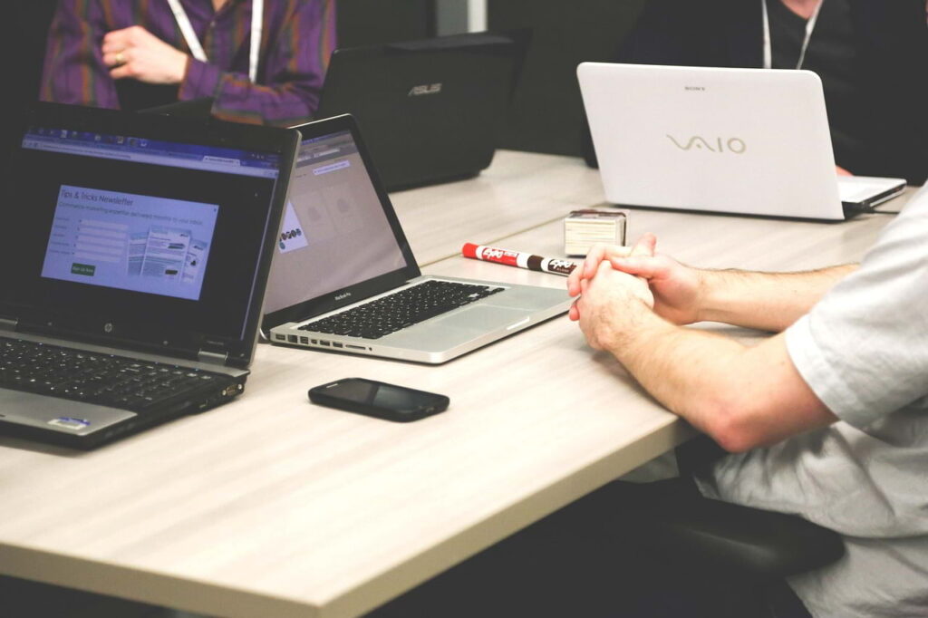 Multiple professionals working on laptops at a desk, showing activity without clear ownership or visible impact in a LinkedIn experience section