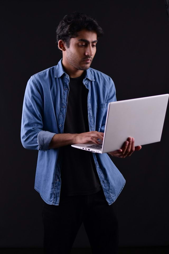Person thoughtfully reviewing a profile on a laptop with a neutral expression