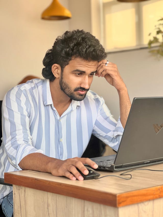 Professional feeling uncertain while reviewing LinkedIn profile, reflecting self-doubt about online credibility