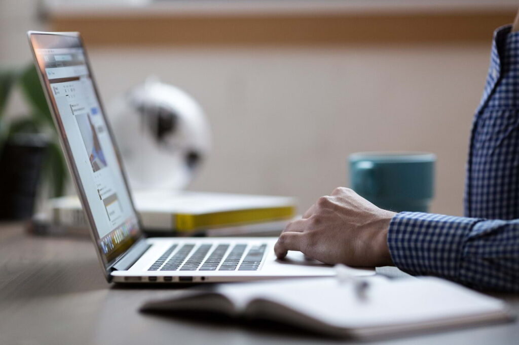 Person casually browsing content on a laptop with minimal attention