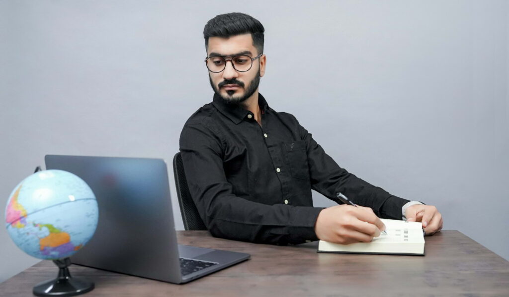 Confident professional working at a clean desk with laptop and notebook in a focused setting