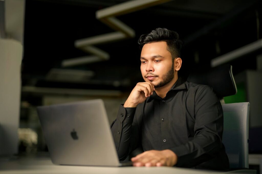 Professional thoughtfully reviewing information on a laptop in a modern office