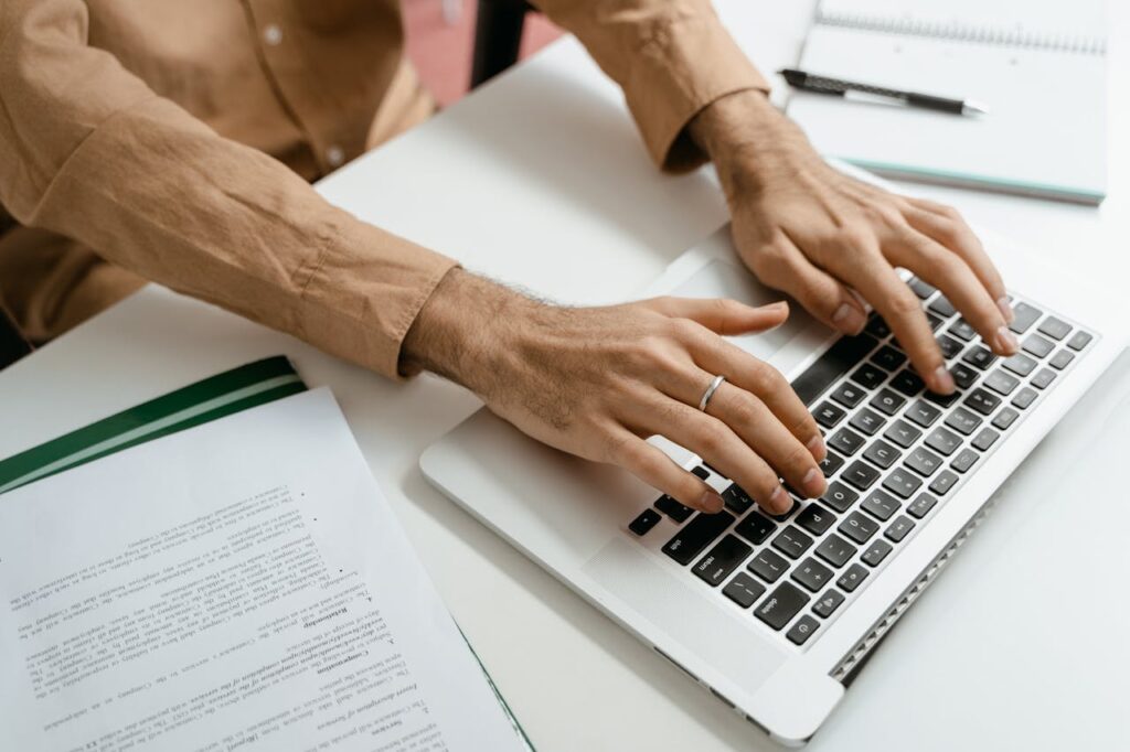Professional working on a laptop beside office documents and notes
