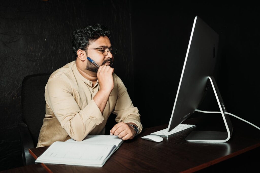 Professional thoughtfully reviewing information on a desktop computer in a quiet office
